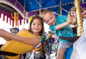 Young boy and girl smiling and riding a carousel together